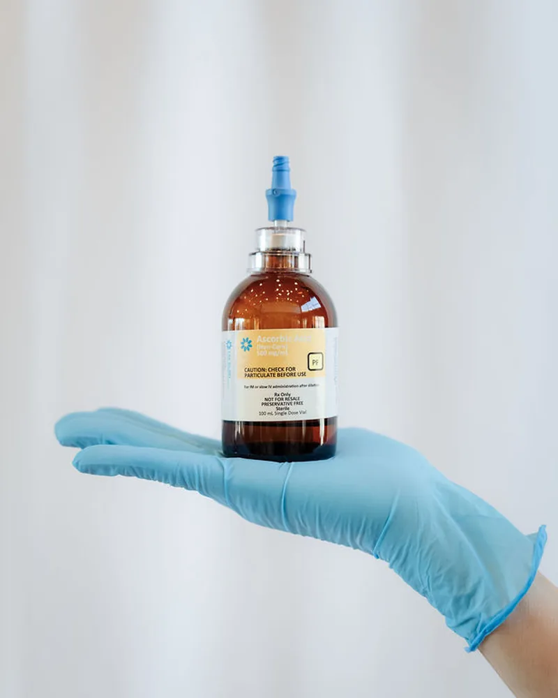 Gloved clinician presenting a vial labeled ascorbic acid